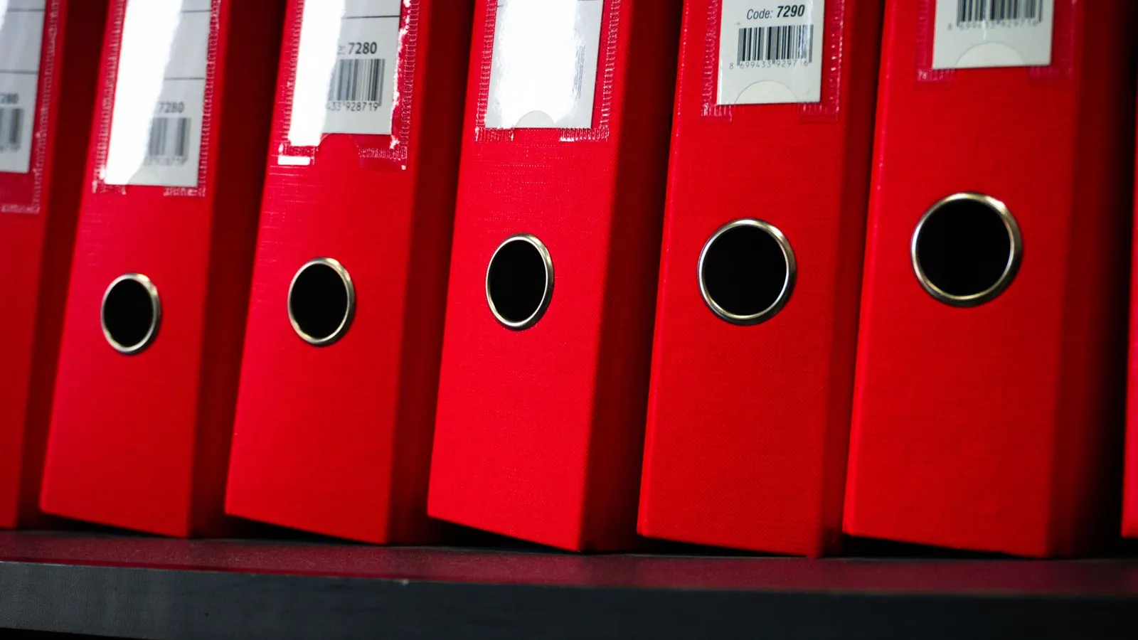 Aufbewahrungsfristen: rote Aktenordner im Regal des Archivs einer GmbH