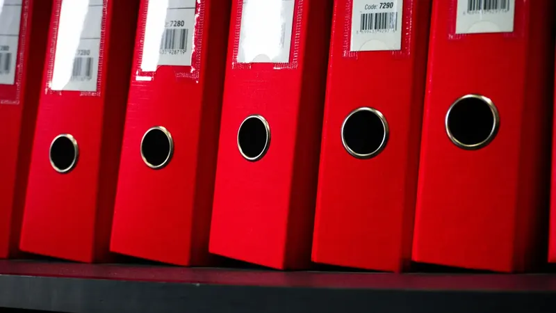 Aufbewahrungsfristen: rote Aktenordner im Regal des Archivs einer GmbH
