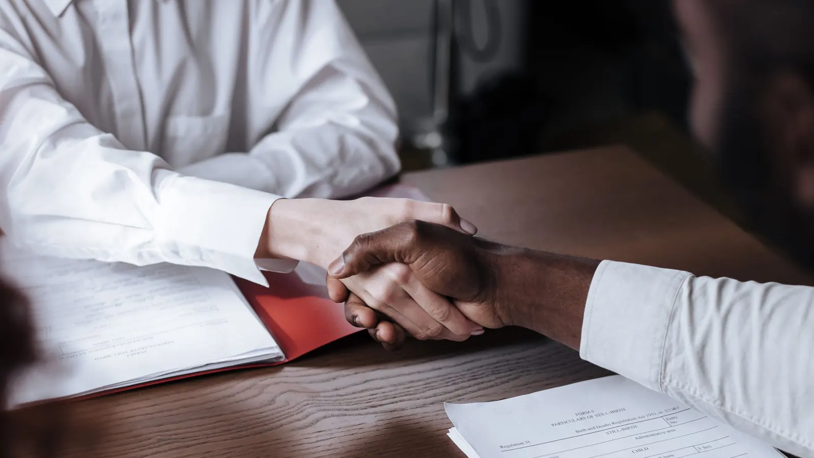 Handschlag über einem Vertrag am Schreibtisch – Gesellschafterdarlehen buchen beginnt mit dem Darlehensvertrag zwischen Gesellschafter und GmbH