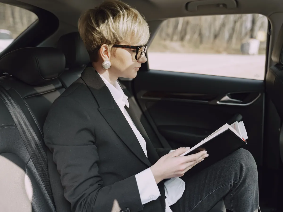 Eine Geschäftsführerin liest im Auto ihre Unterlagen – der Firmenwagen der GmbH im Alltag
