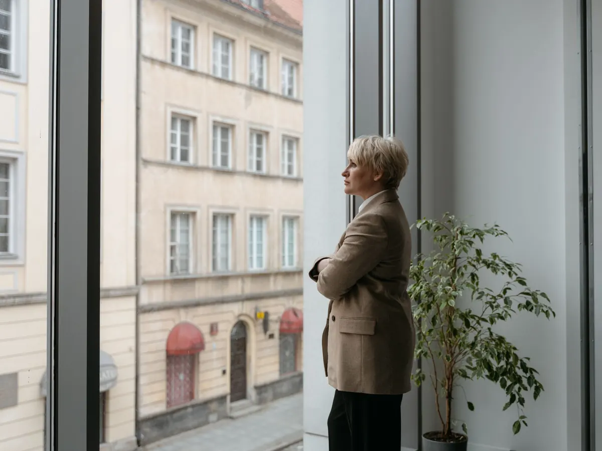 Eine Geschäftsführerin steht am Fenster ihres kleinen Büros – das Geschäftsführergehalt der Gesellschafterin in der GmbH