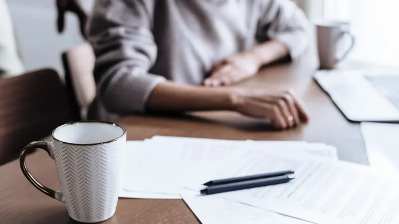 Papiere, Stifte und eine Tasse auf dem Schreibtisch – die monatliche Abrechnung, bevor das Geschäftsführergehalt gebucht wird