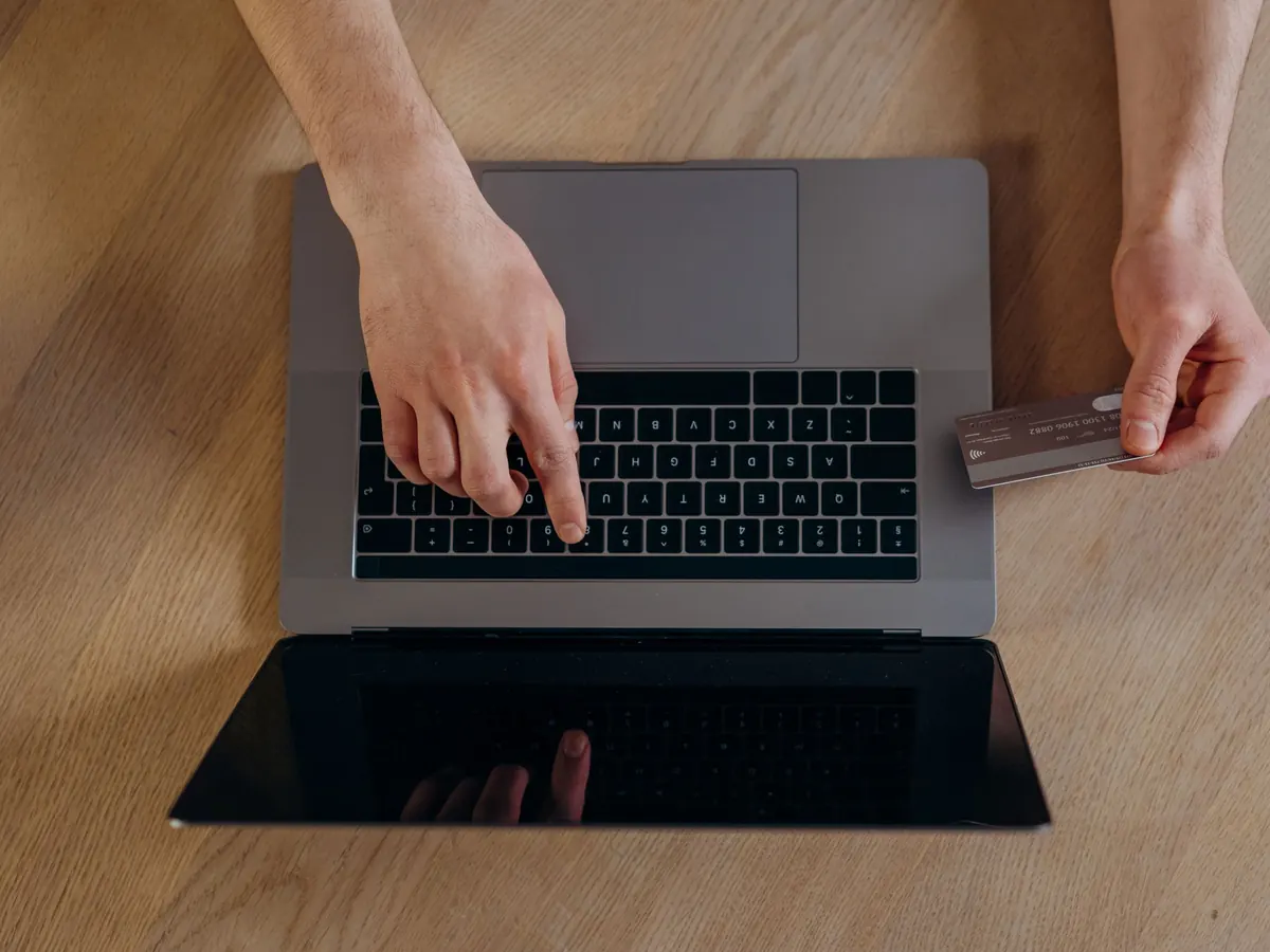 Hände am Laptop mit einer Bankkarte – die Zahlungen zum Geschäftsführergehalt an Finanzamt, Krankenkasse und Geschäftsführer