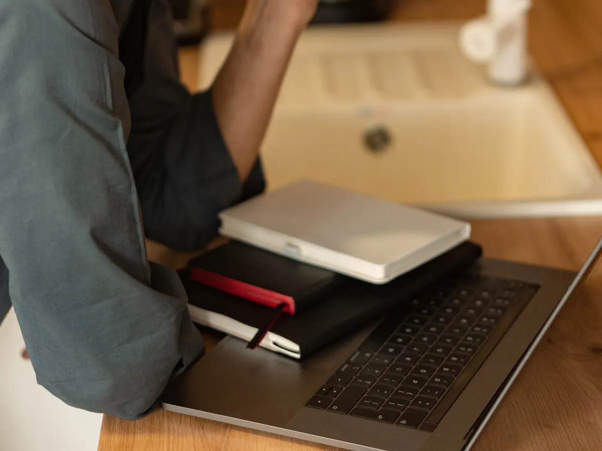 Notizbücher auf dem Laptop am Küchentisch – die Entscheidung für eine Rechtsform in Ruhe vorbereiten