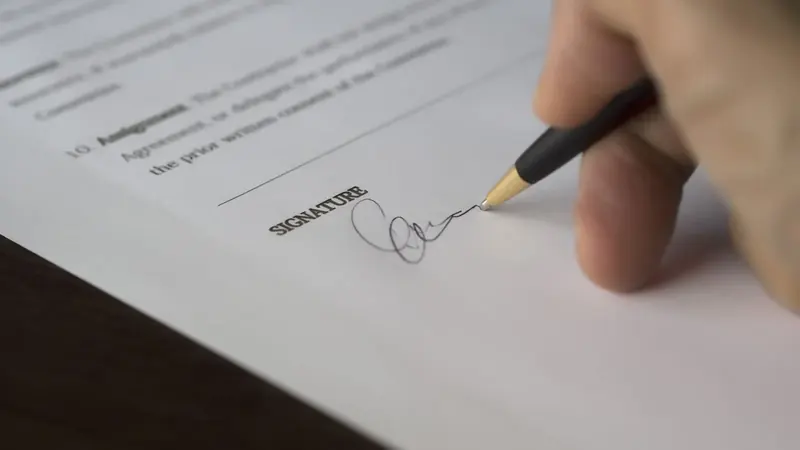 Eine Hand unterschreibt mit dem Füller einen Vertrag – UG gründen: die Kosten beginnen beim Notartermin