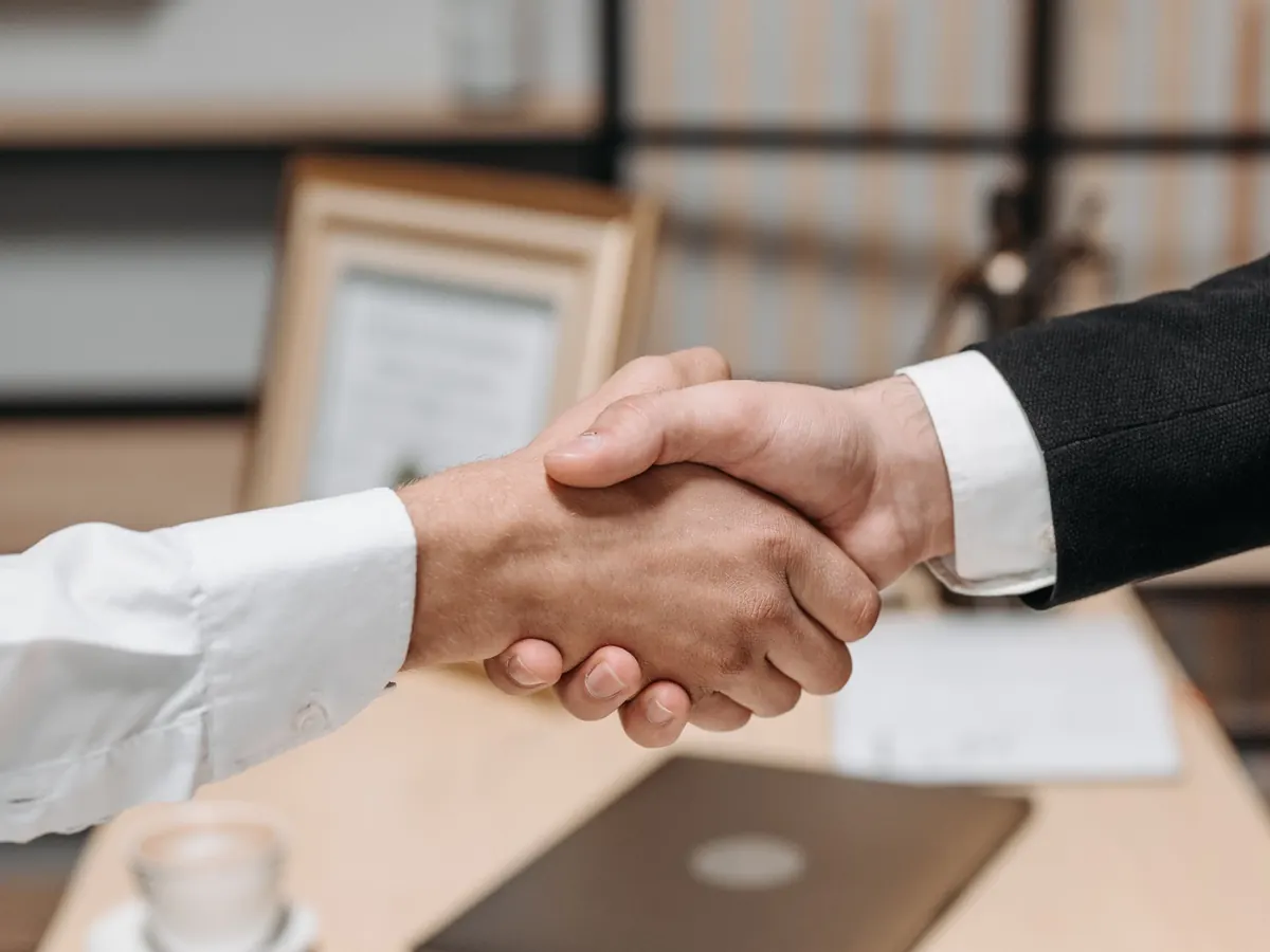 Handschlag über dem Schreibtisch – nach dem Notartermin beginnen die Kosten der UG-Gründung