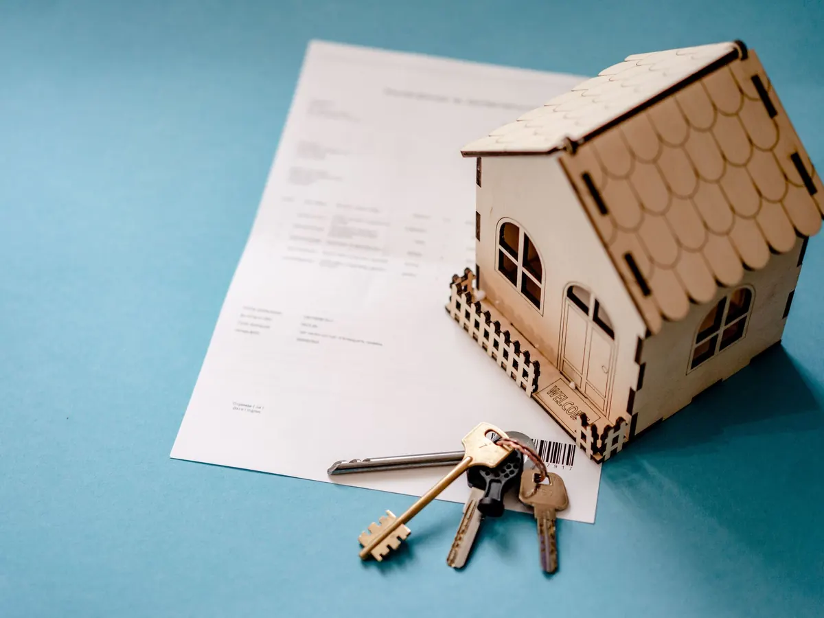 Schlüsselbund und Hausmodell auf einem Vertrag – Vermietung durch eine Immobilien-GmbH und die Gewerbesteuer