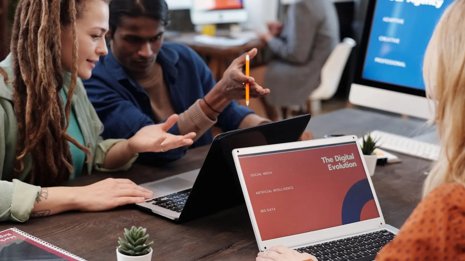 Ein Team einer Agentur bespricht am Tisch einen Entwurf auf dem Laptop