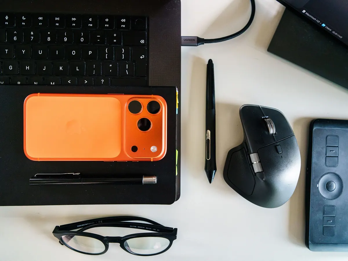 Aufgeräumter Schreibtisch mit Tastatur, Maus, Telefon und Brille