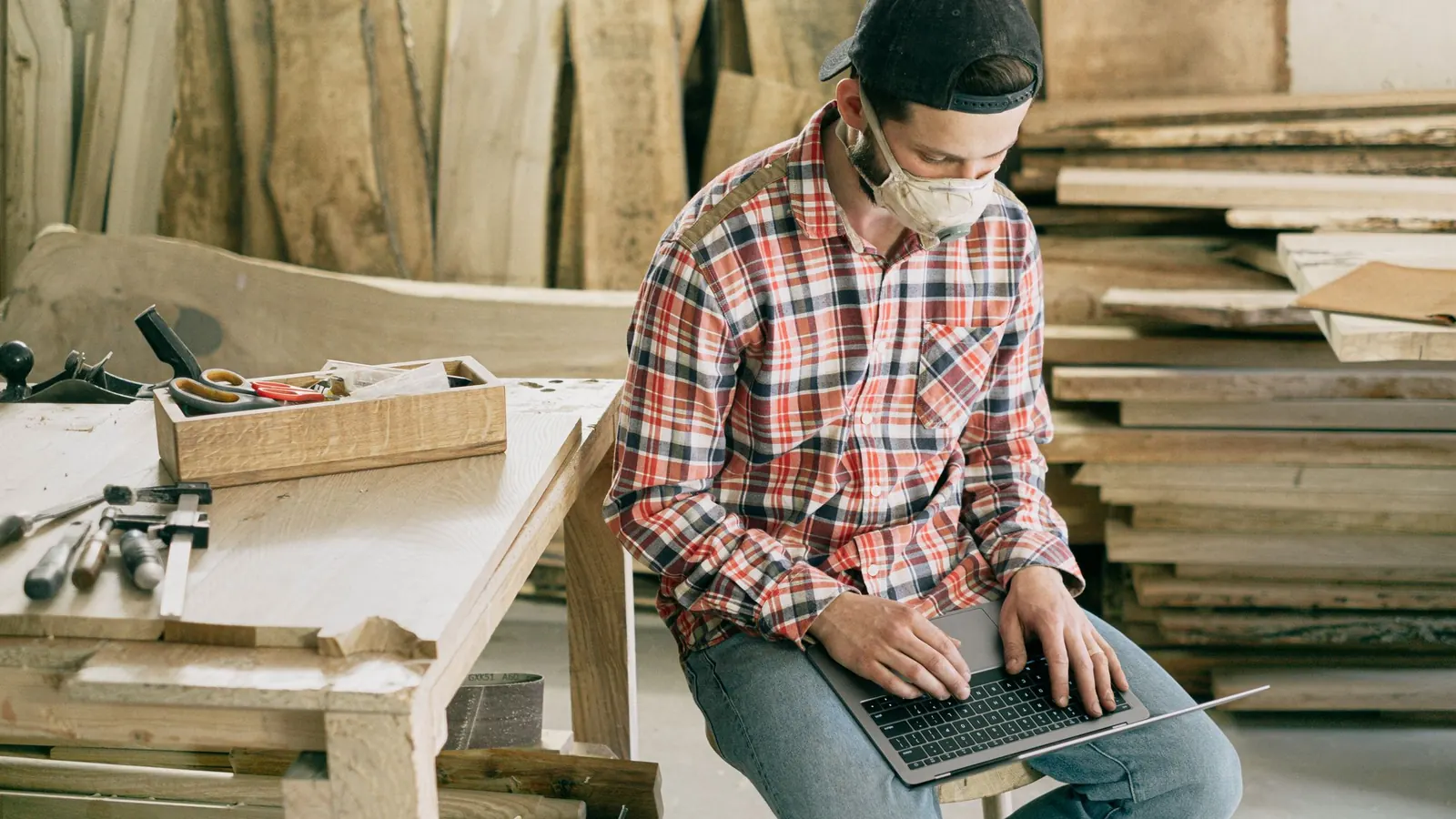 Ein Tischler arbeitet in seiner Werkstatt am Laptop – Gewerbesteuer berechnen
