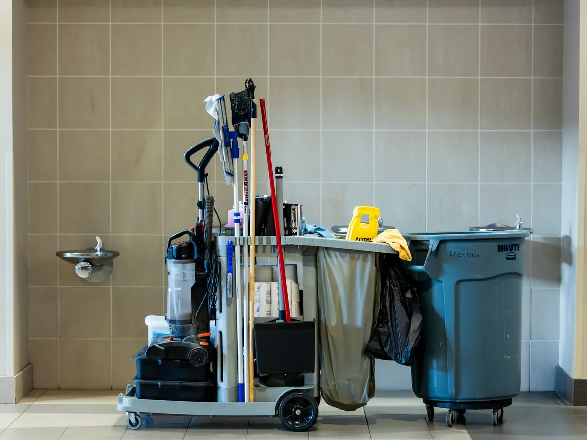 Ein Reinigungswagen mit Eimer, Wischmopp und Müllsack im Flur eines Gebäudes