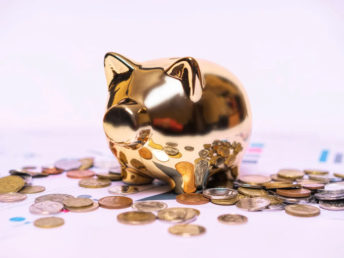 Ein goldenes Sparschwein auf Unterlagen mit Münzen
